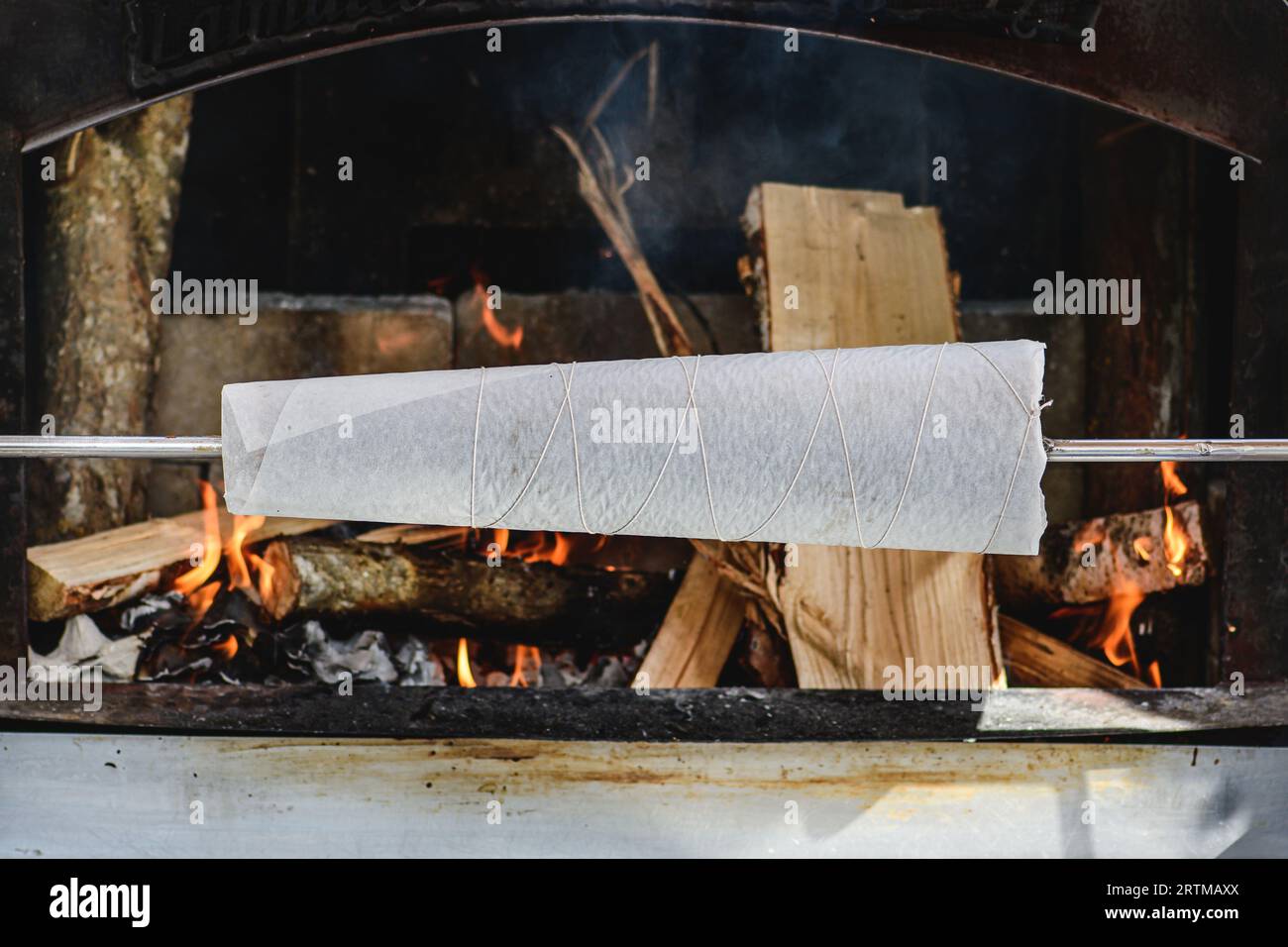 Initial stage of preparation of a tree cake, Lithuanian šakotis, Polish sękacz, Belarusian bankucha, German baumkuchen cooked over an open fire Stock Photo