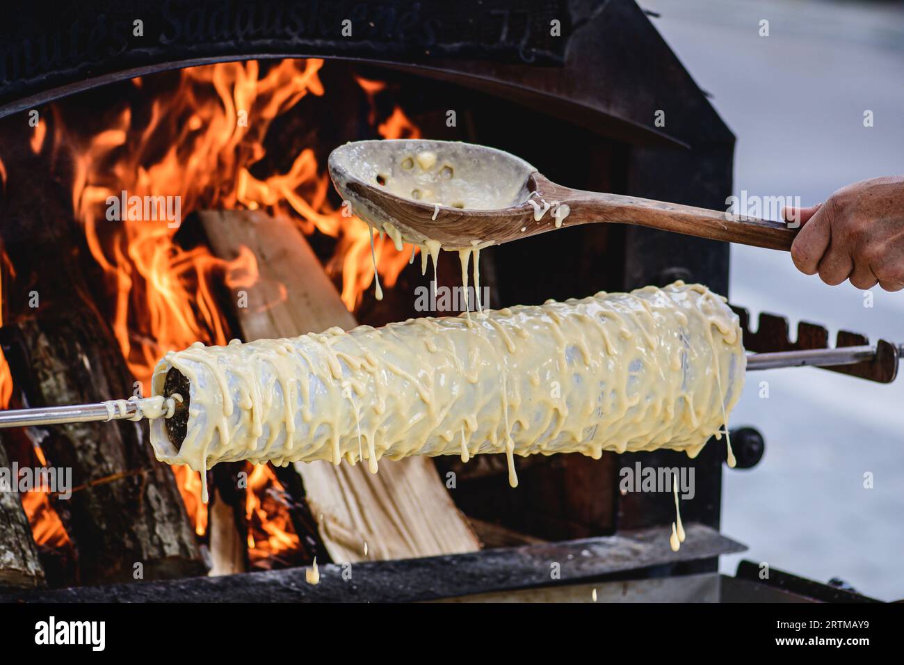 Initial stage of preparation of a tree cake, Lithuanian šakotis, Polish sękacz, Belarusian bankucha, German baumkuchen cooked over an open fire Stock Photo