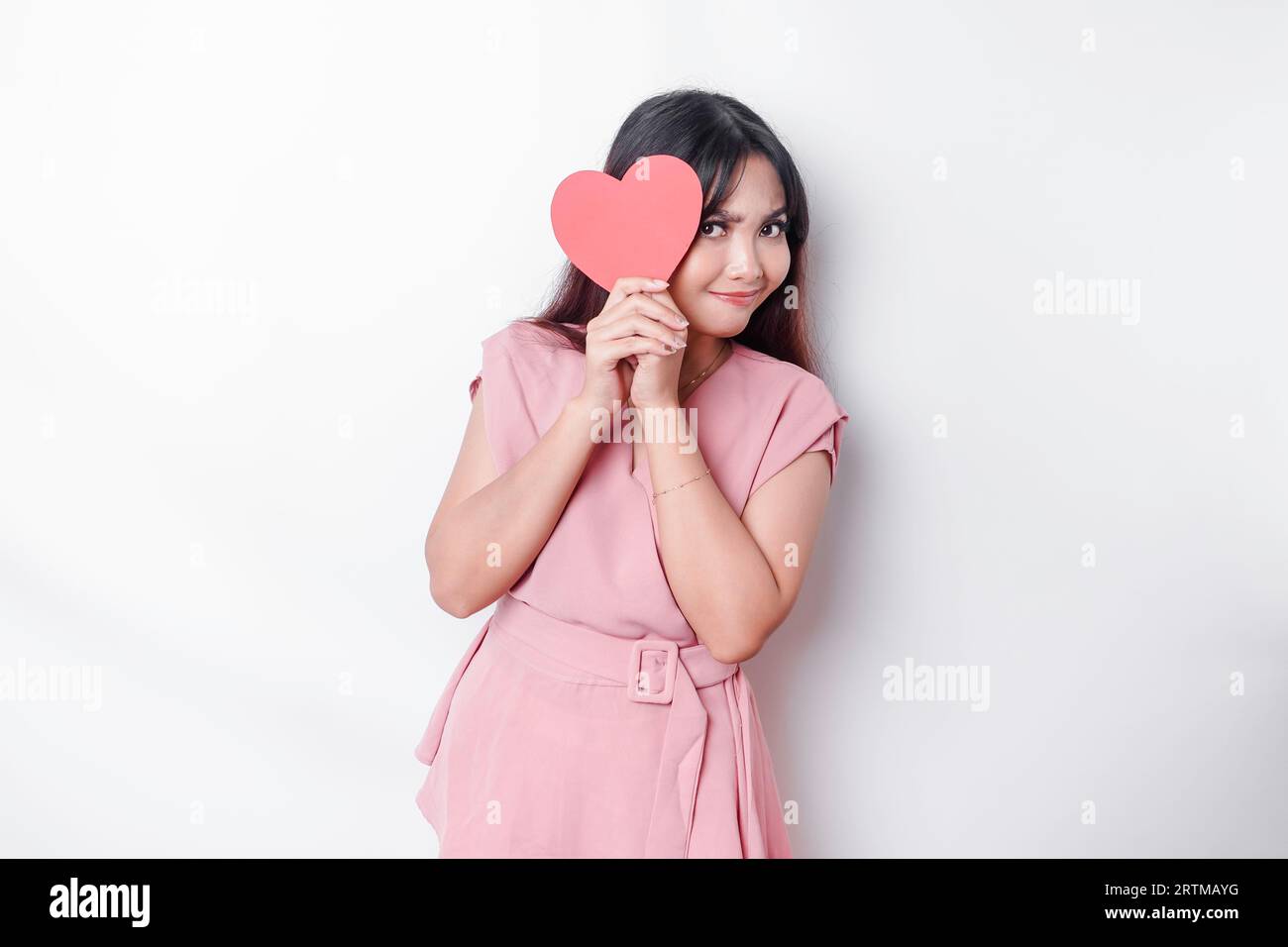 Cute and shy Asian girl blushing, giving a red heartshaped paper