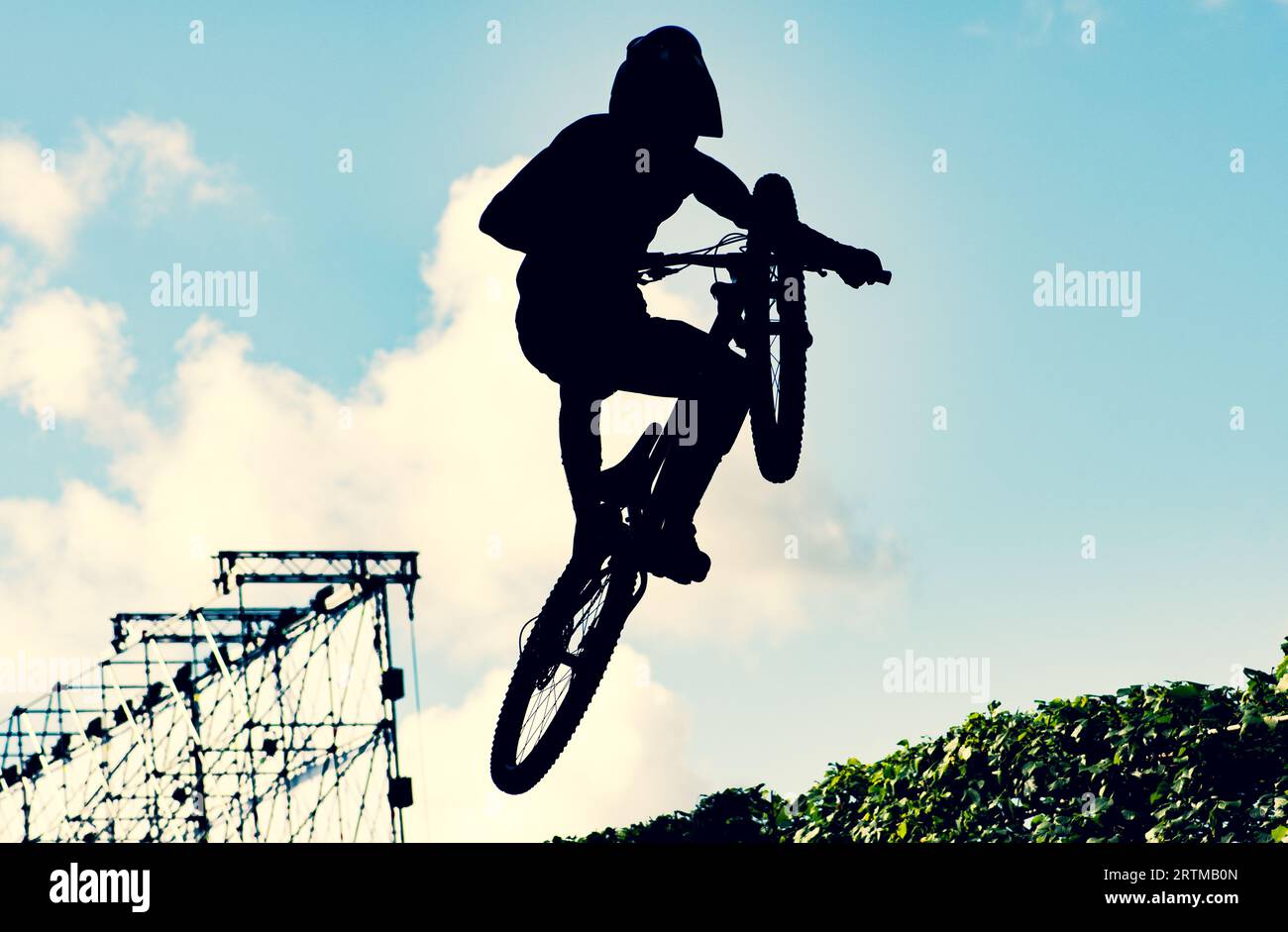 Silhouette of a biker performing an extreme dirty jump with a bmx bike