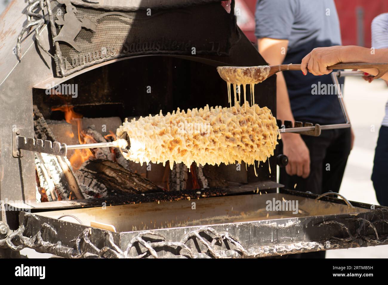 Initial stage of preparation of a tree cake, Lithuanian šakotis, Polish sękacz, Belarusian bankucha, German baumkuchen cooked over an open fire Stock Photo