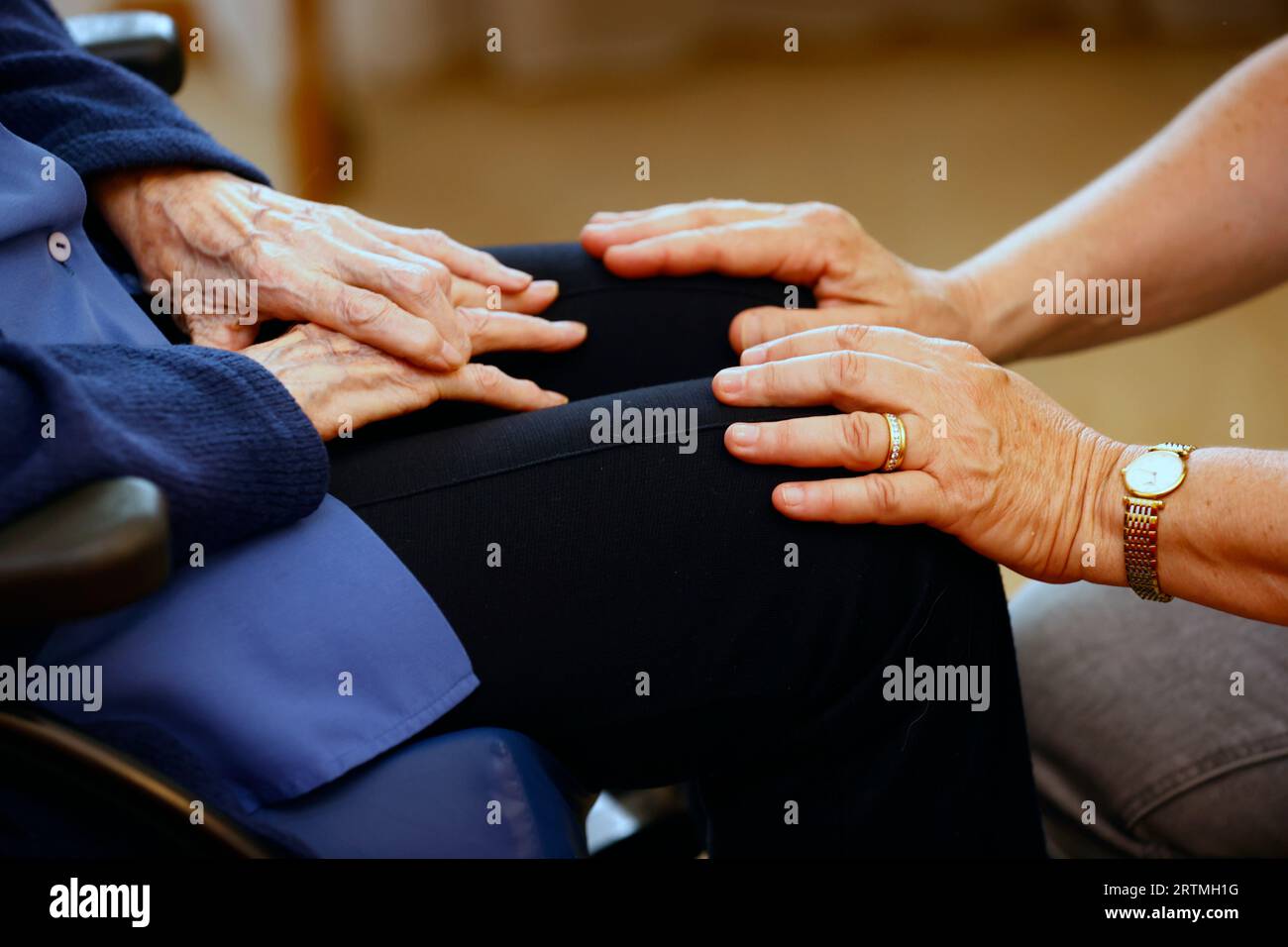 Retirment home.  Close up of care assistants hand reassuring senior woman. Stock Photo