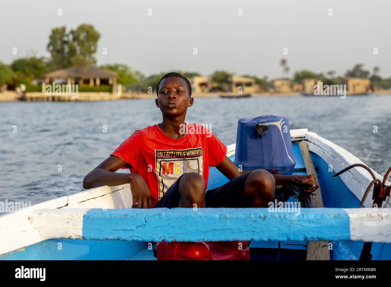 Boy steering a boat on a waterway in Saloum, Senegal Stock Photo