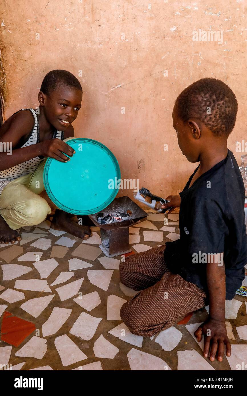 Boys poking a fire at home in Thiaoune, Senegal Stock Photo