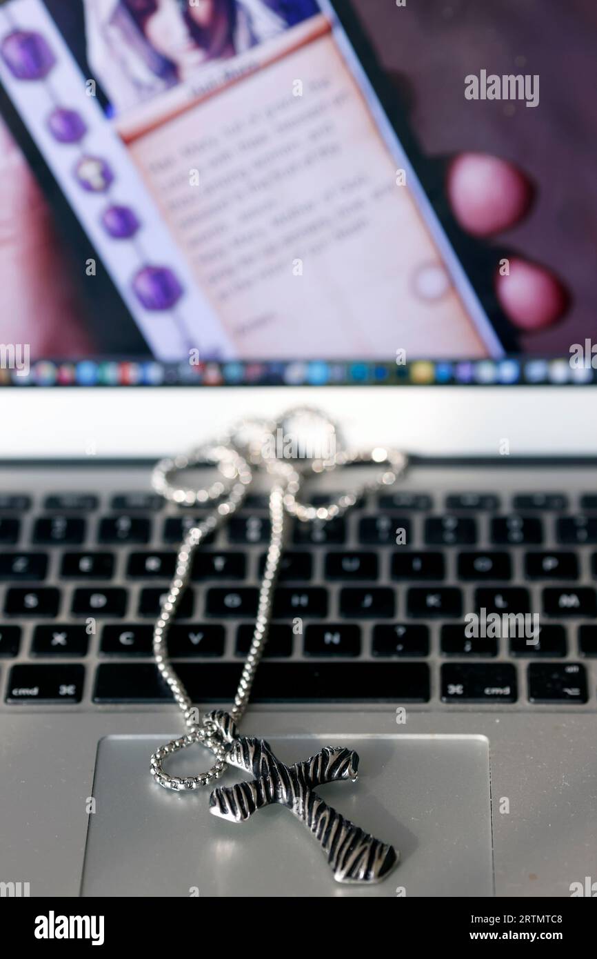 Silver christianity cross pendant  on a laptop. Religious and digital symbols. Stock Photo