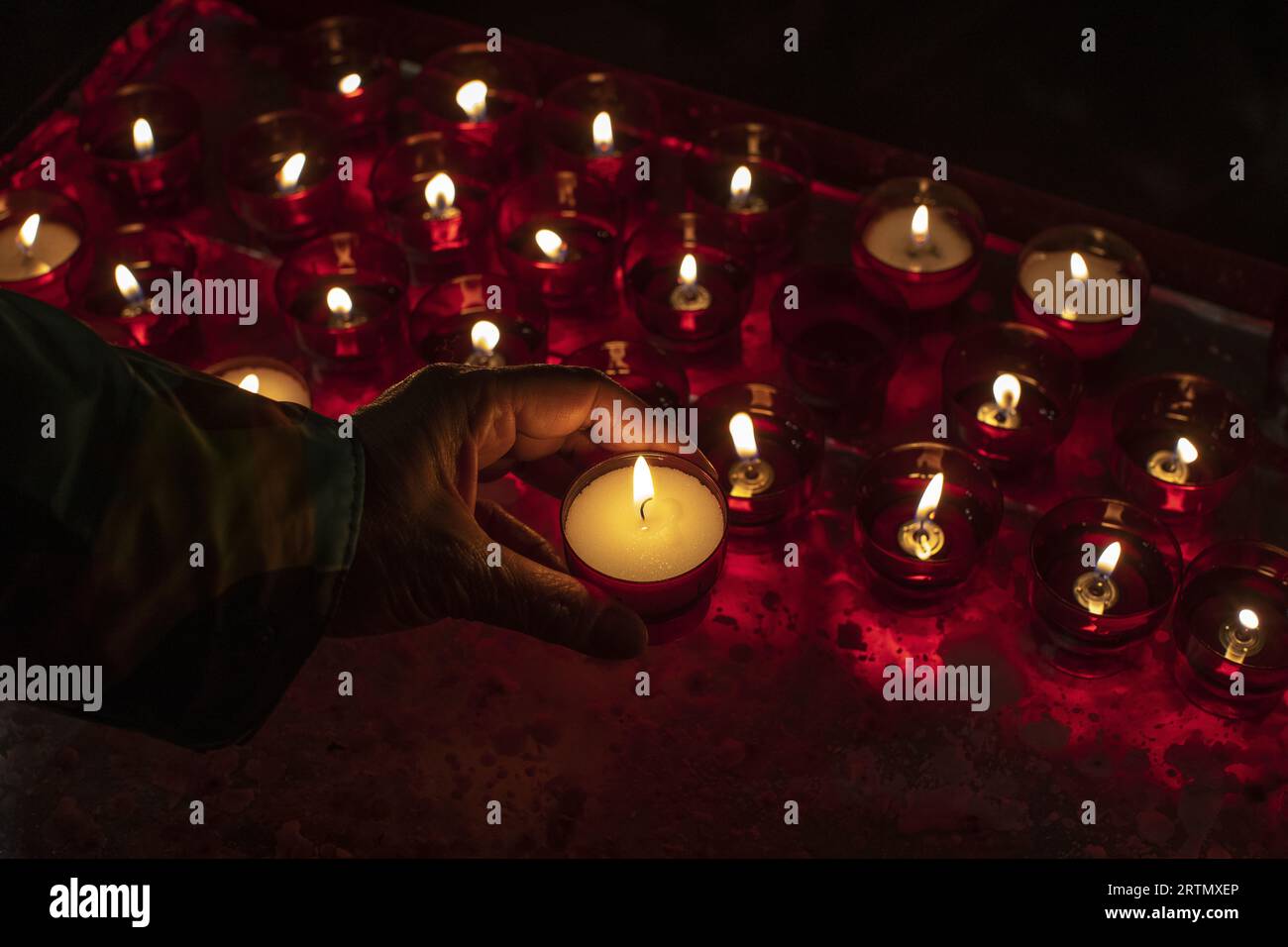 Woman lighting a candle in front of a Virgin Mary statue in Notre Dame