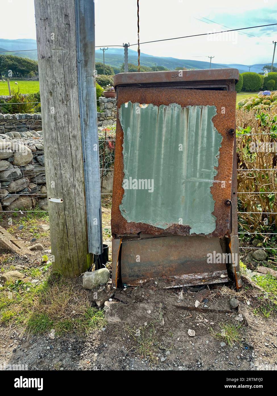 Vintage rusty GPO junction box by a telegraph pole. Barmouth, Wales, UK. Stock Photo