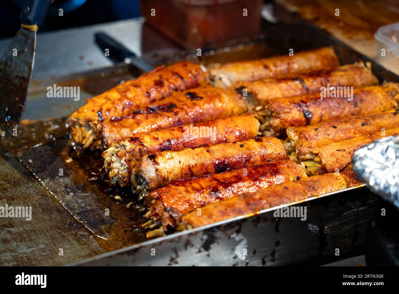 Grilling barbecue meatloaf rolled with vegetables, pork or beef at traditional night market stall, delicious street food in South Korea. Stock Photo