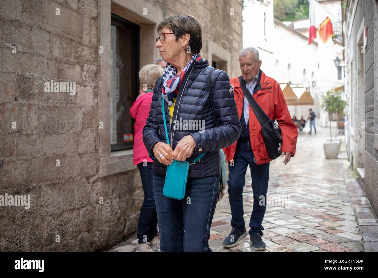 Kotor, Montenegro, Apr 17, 2023: Senior tourists walking down the narrow cobblestone street of Old Town Stock Photo