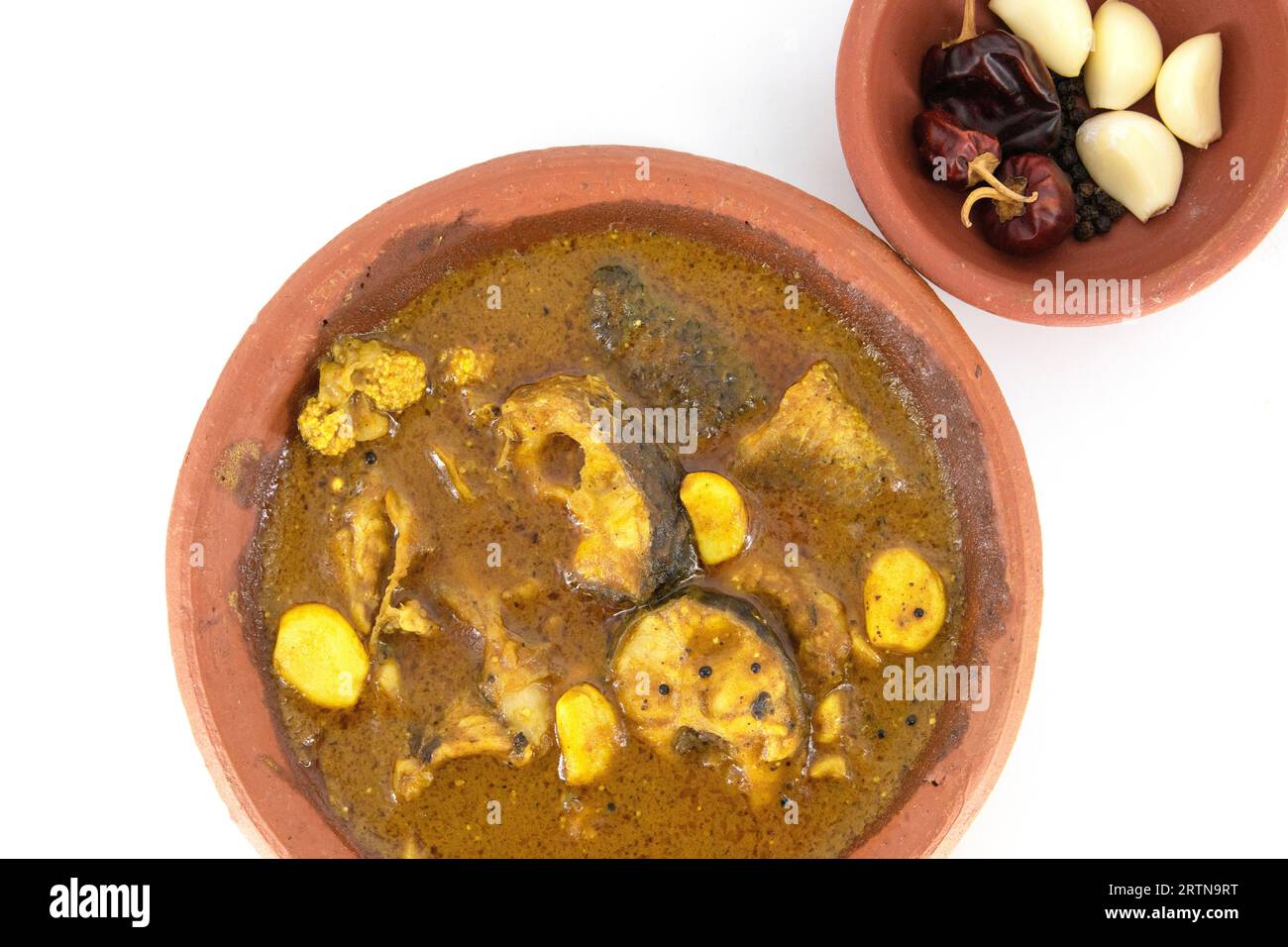 ish curry served in traditional mud pot with fish curry ingredient. Fresh fish curry with chilli, pepper and garlic. Special south Indian fish curry. Stock Photo