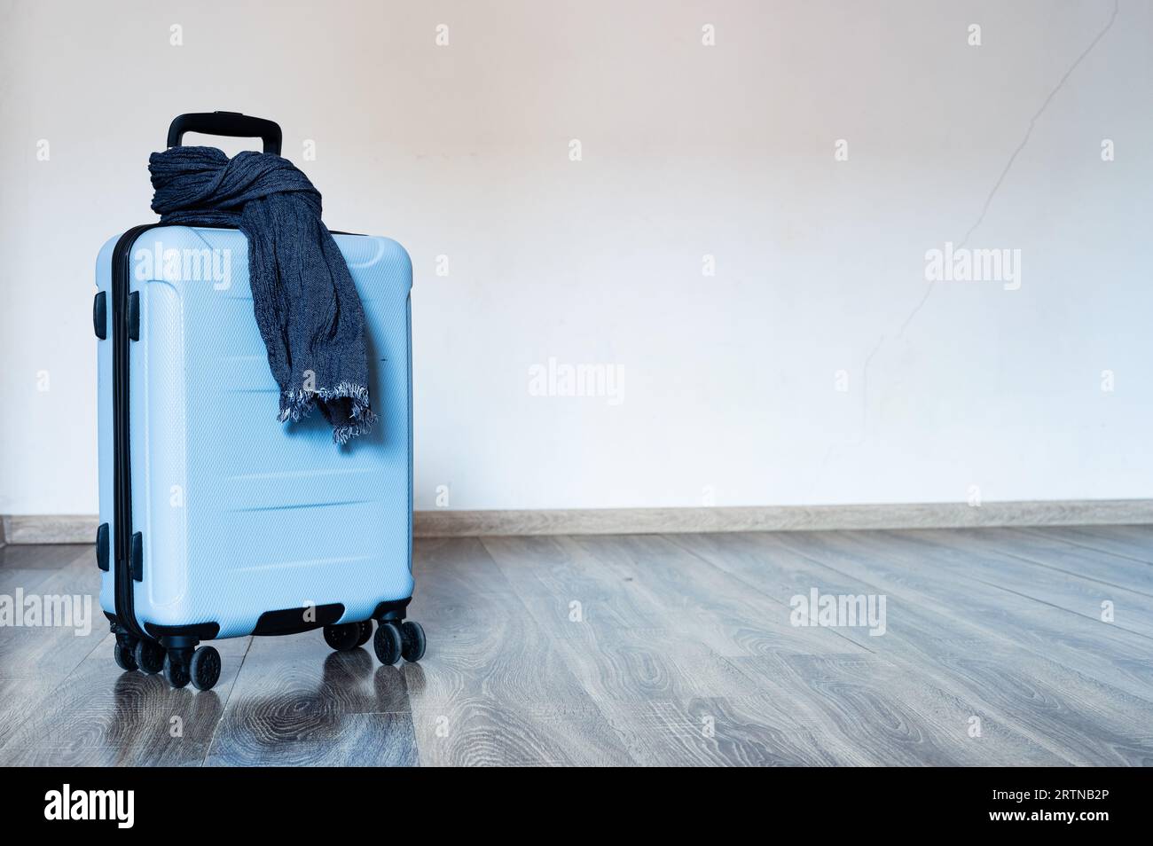 Packed blue travel bag on wheels with scarf around handle. Copyspace, background Stock Photo