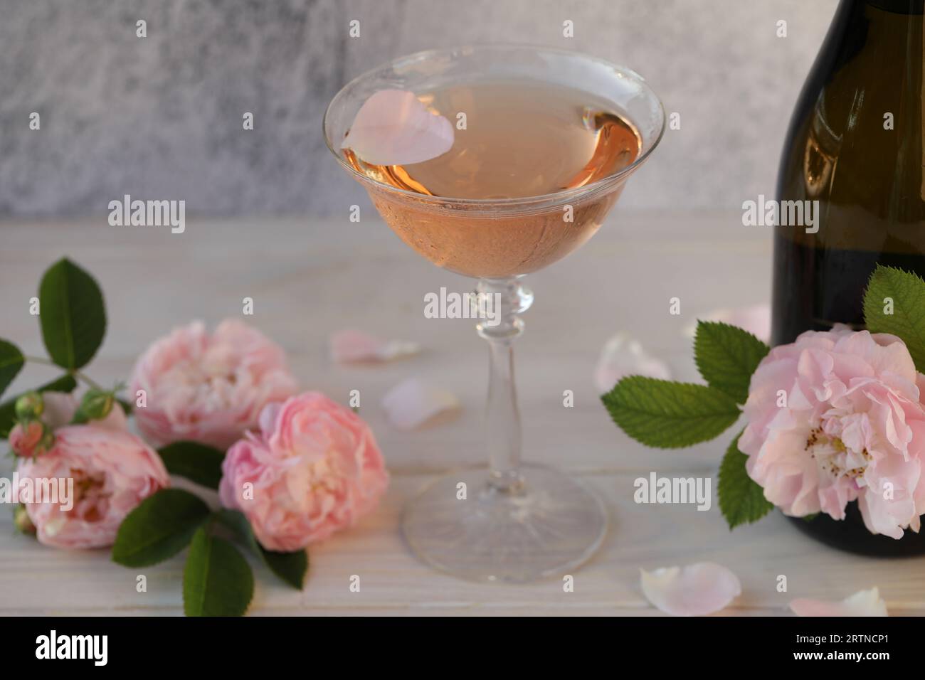 Glass of pink champagne with rose flowers on the light grey background Stock Photo