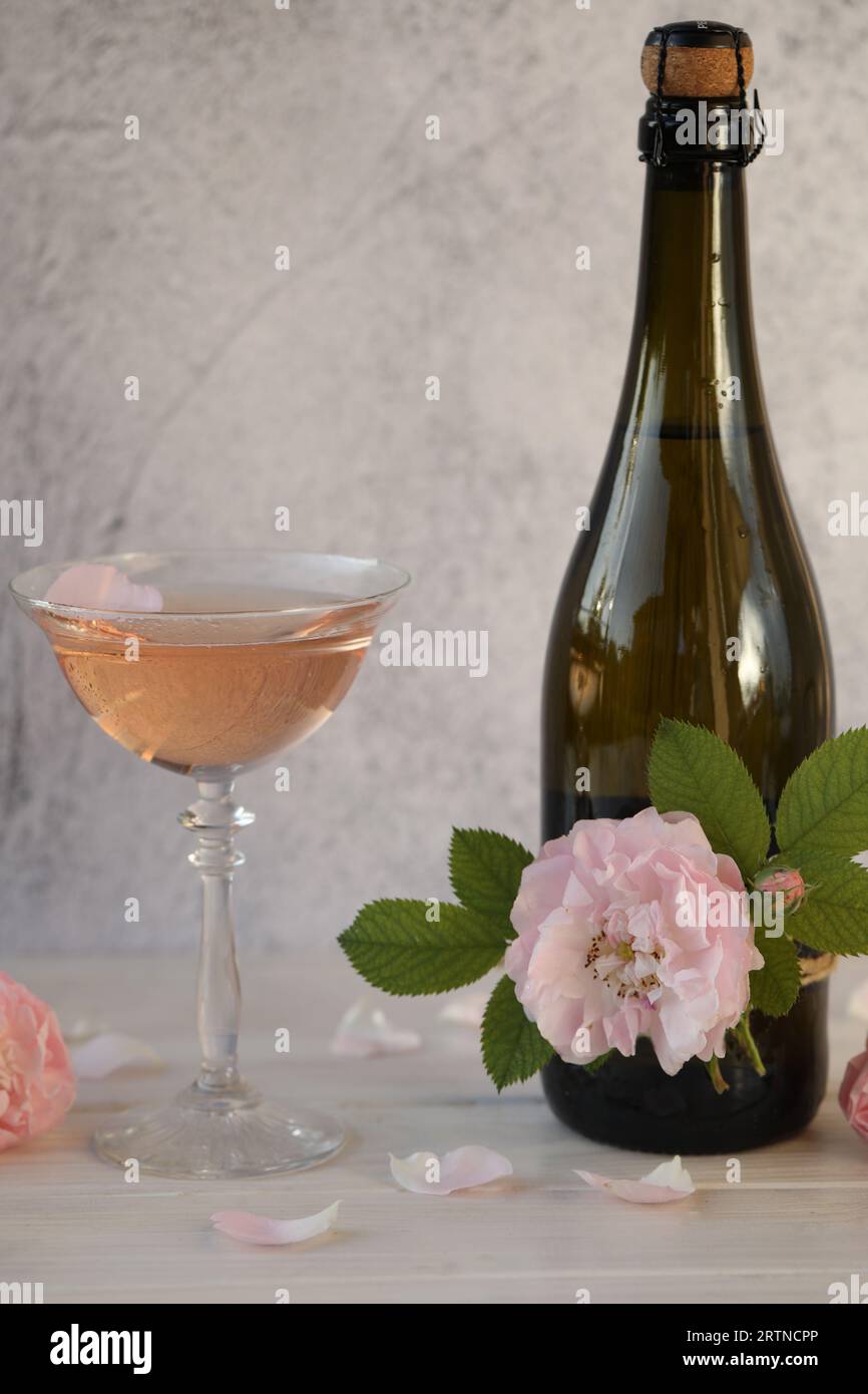 Glass of pink champagne with rose flowers on the light grey background ...