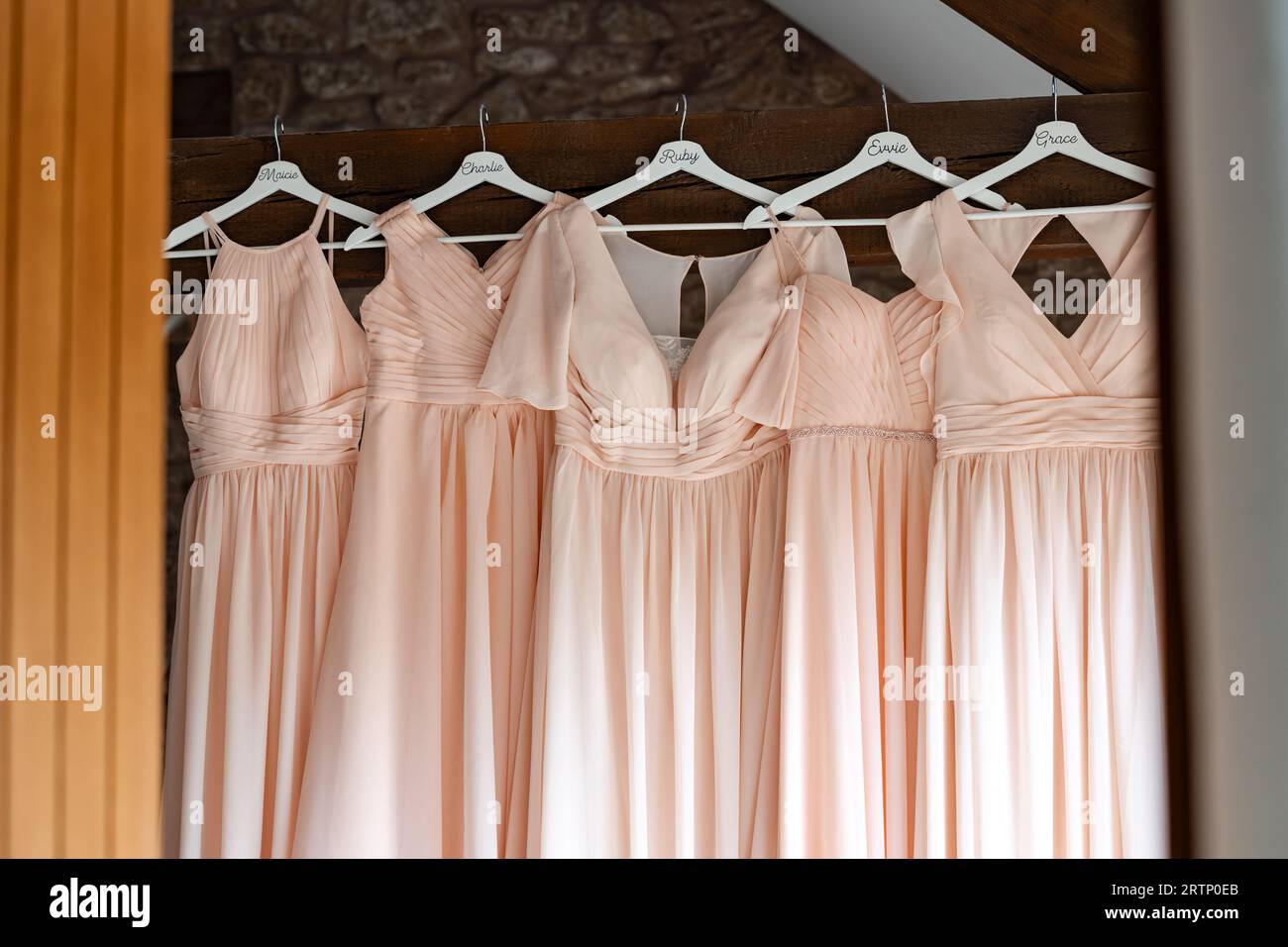 Bridesmaids dresses hanging from wooden beam at wedding venue Stock ...