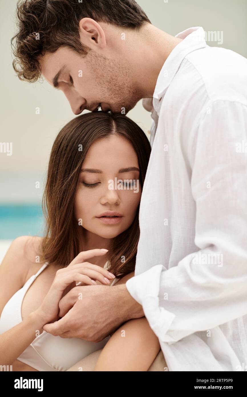 couple bonding and trust, handsome man kissing head of beautiful woman, romantic getaway concept Stock Photo