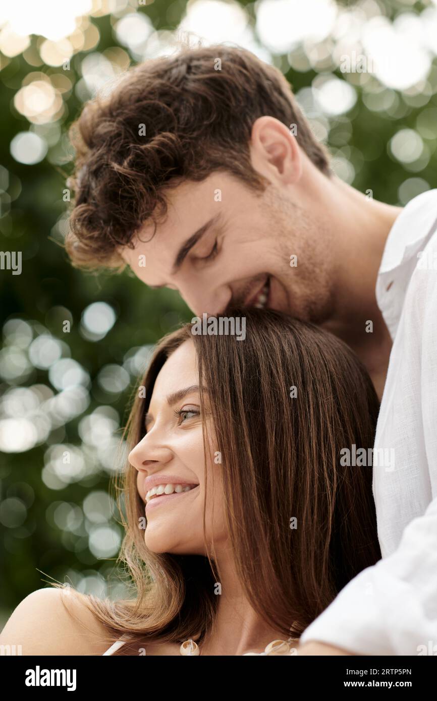 couple bonding and trust, cheerful man kissing head of beautiful woman, romantic getaway concept Stock Photo