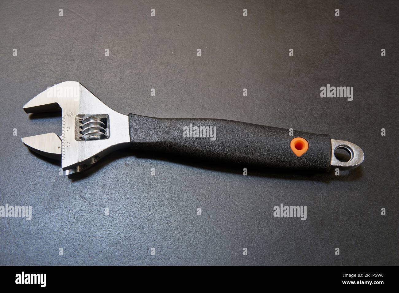 Adjustable wrench with measuring tool on black wooden table Stock Photo