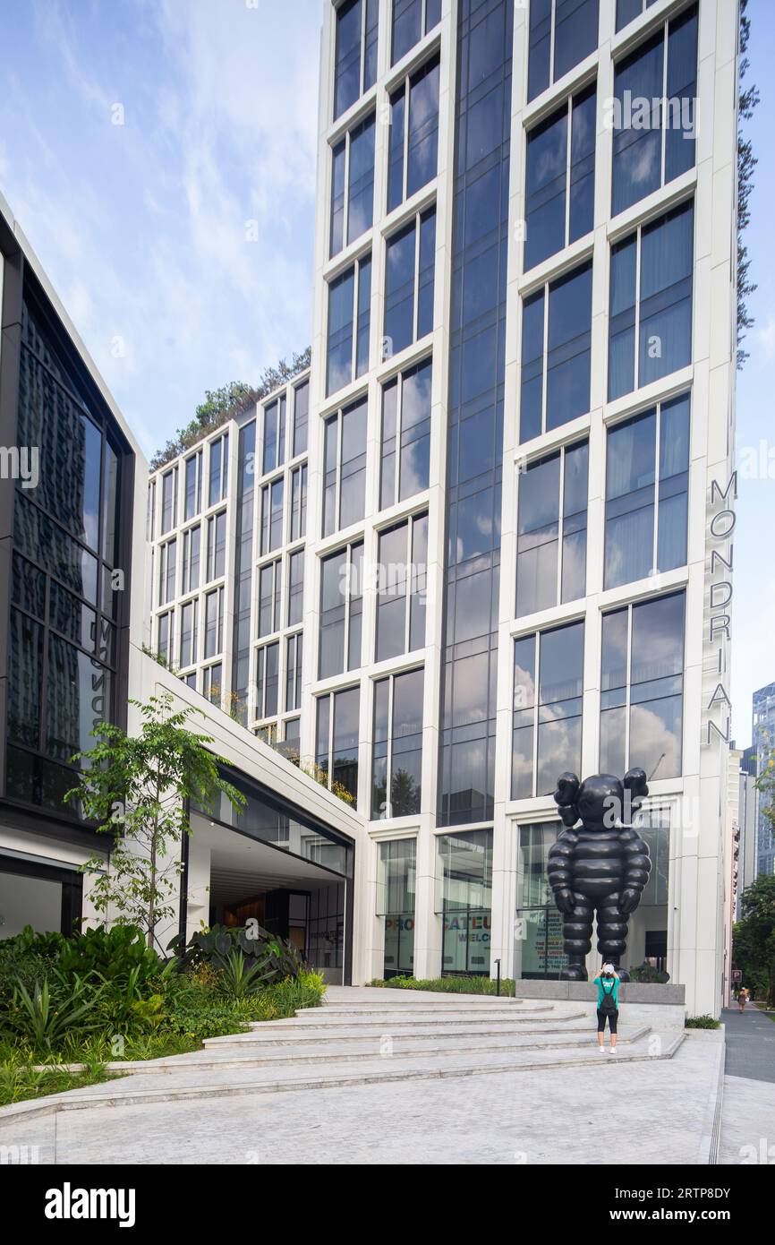 A lady with a backpack is taking picture of the 6m KAWS sculpture, What