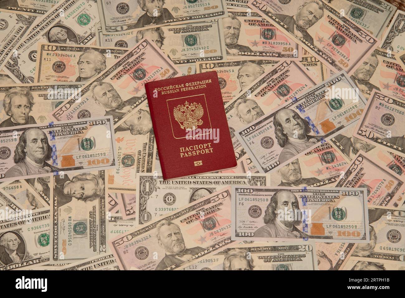 A foreign Russian passport lies on scattered dollar bills Stock Photo