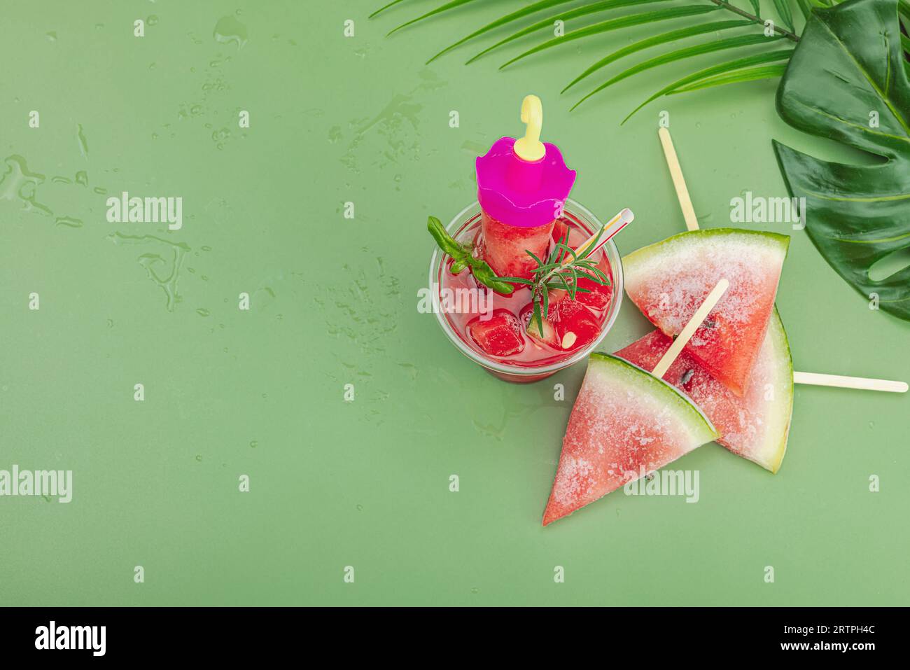 Refreshing watermelon cocktail. Traditional summer drink. Trendy Savannah green background, palm leaves, top view Stock Photo