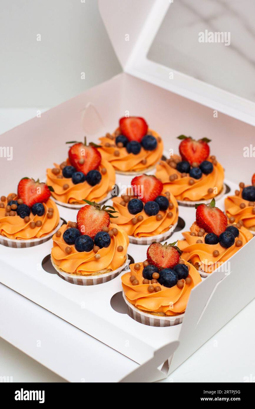 Orange cupcakes with fresh berries and buttercream frosting in the gift