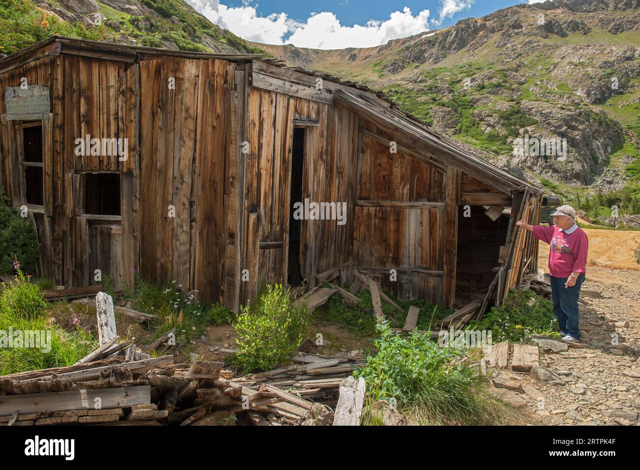 An elderly woman from South Park inspects the ruins of a miner's cabin at the historic Missouri Mine near Bailey, Colorado Stock Photo