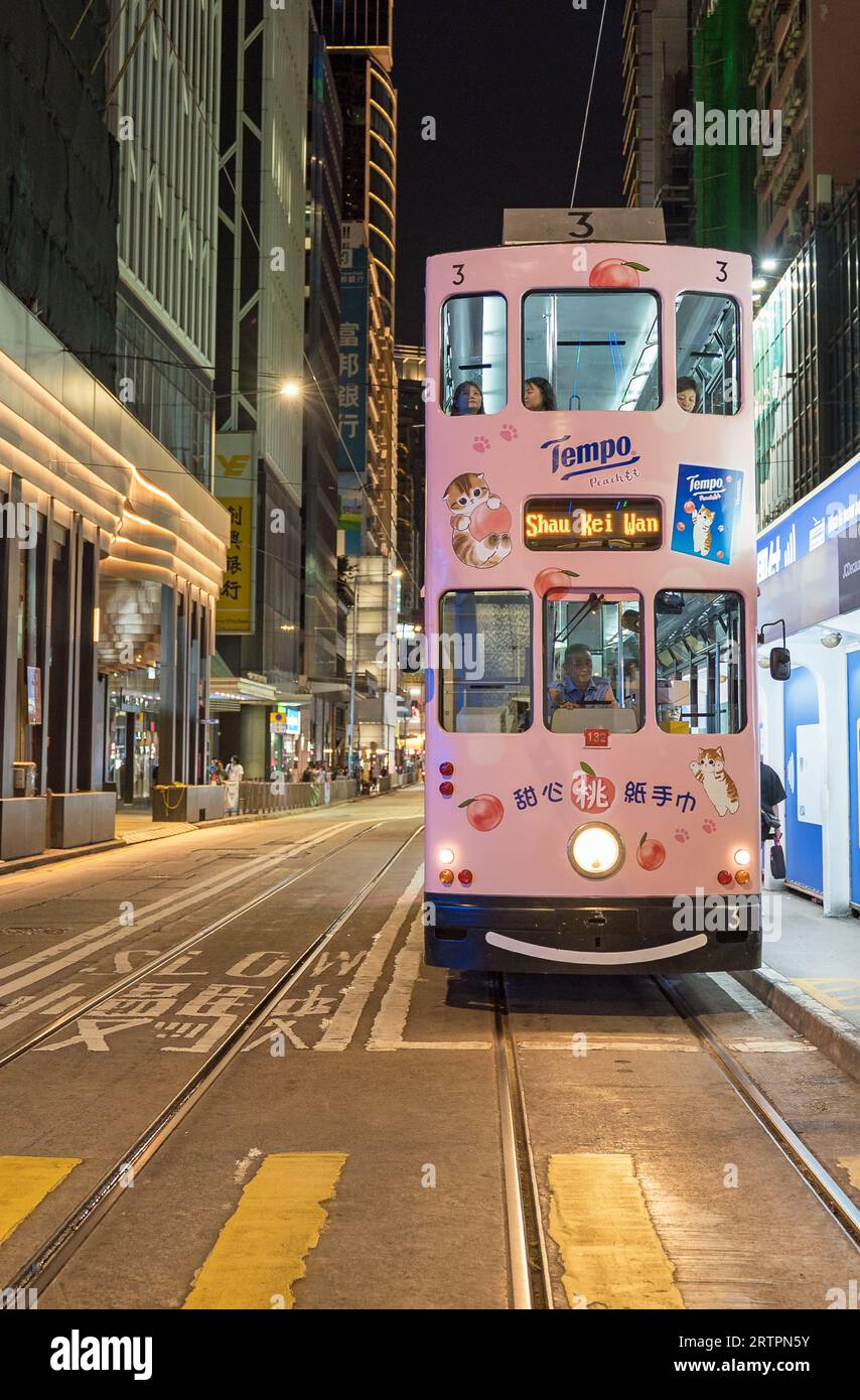 Old pink Hong Kong tram in the road stopped at a crossing at night. Hong Kong - 27th August 2023 Stock Photo