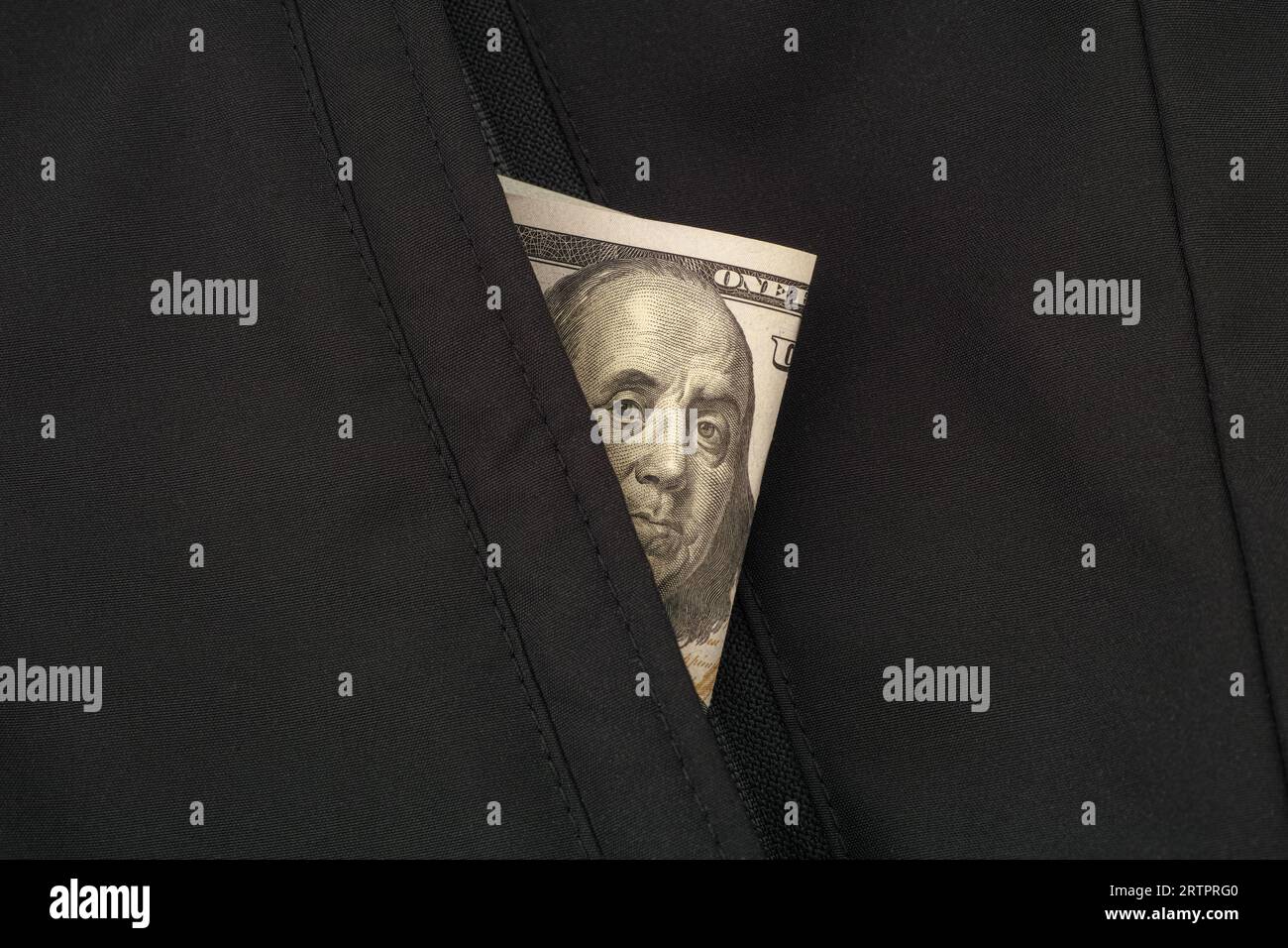 A one hundred dollar bill in the pocket of a black jacket. Close up. Stock Photo
