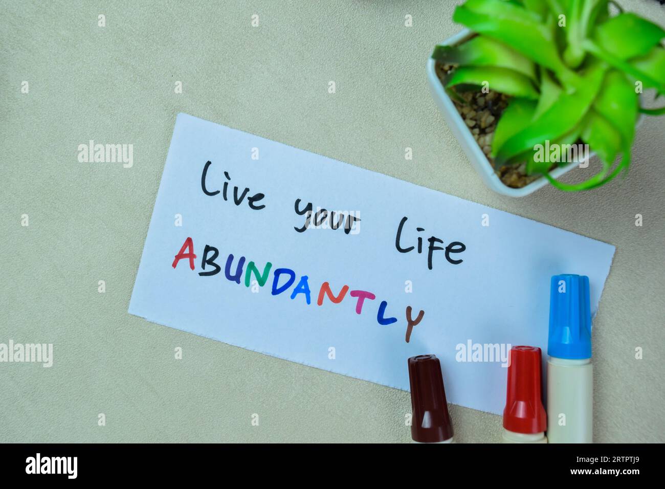 Concept of Live Your Life Abundantly write on sticky notes isolated on Wooden Table. Stock Photo