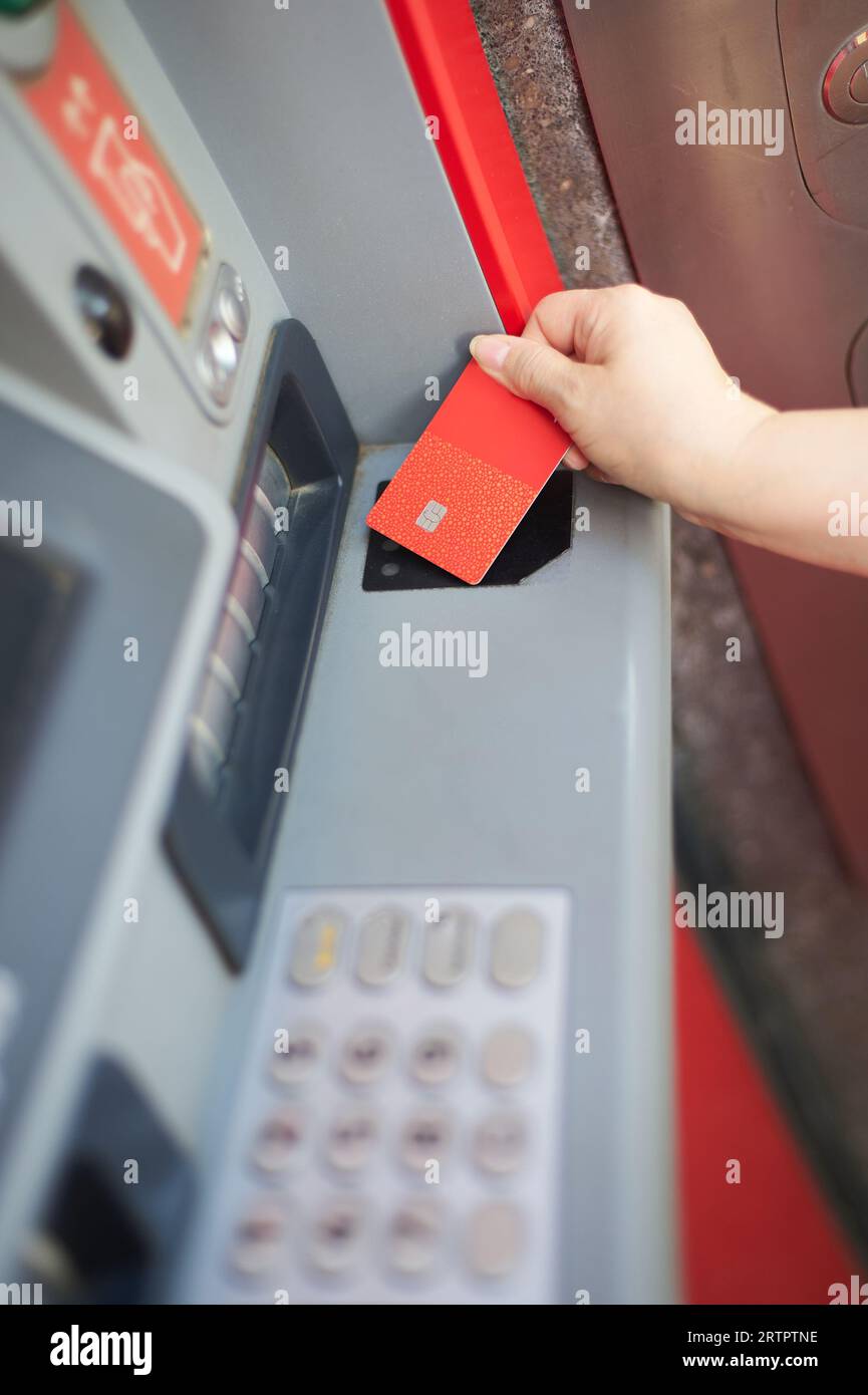 Unrecognizable woman's hand using your credit card at an ATM in selective focus. Stock Photo