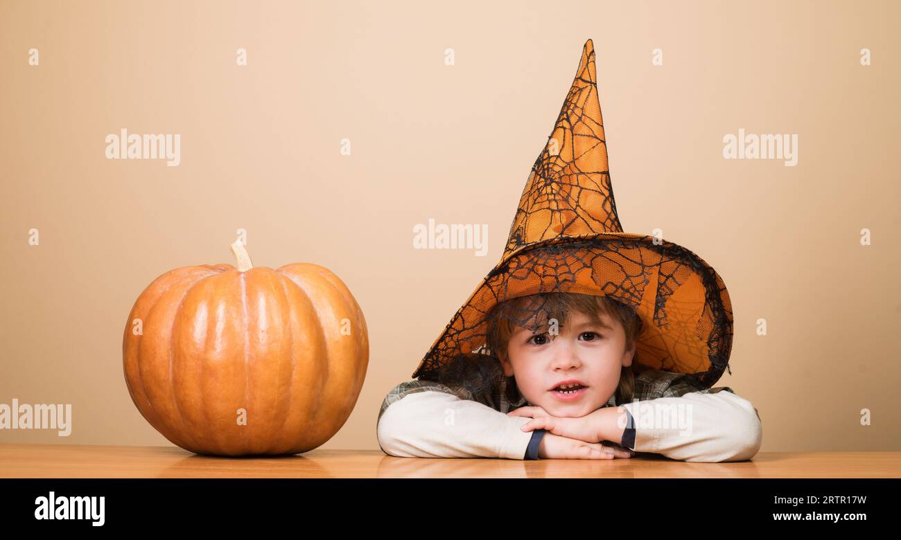 Little kid boy in witch hat with Halloween pumpkin. Preparation for Halloween holiday. Thanksgiving day cooking. Halloween child with jack-o-lantern Stock Photo