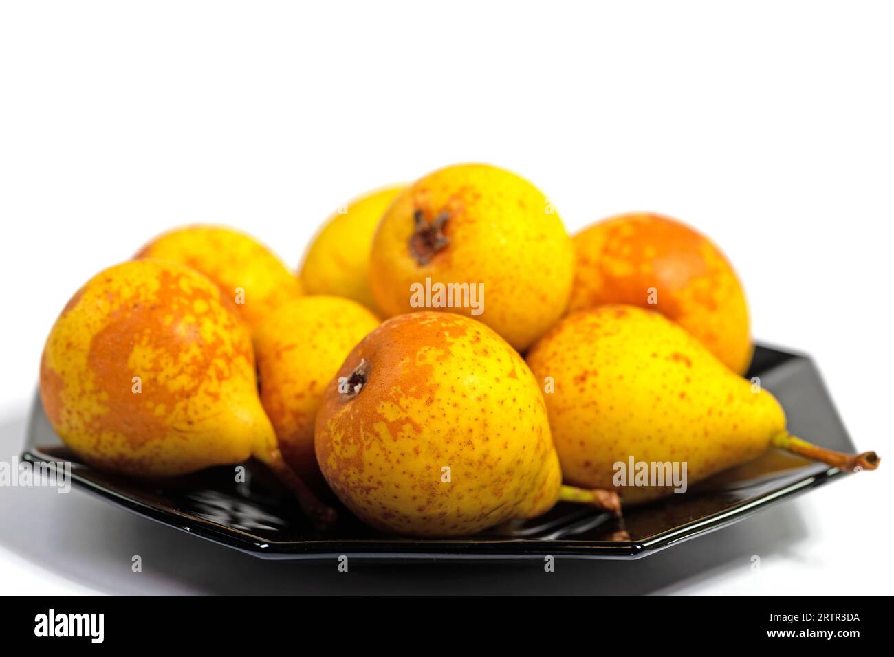Ripe pears on a black plate against a white background Stock Photo