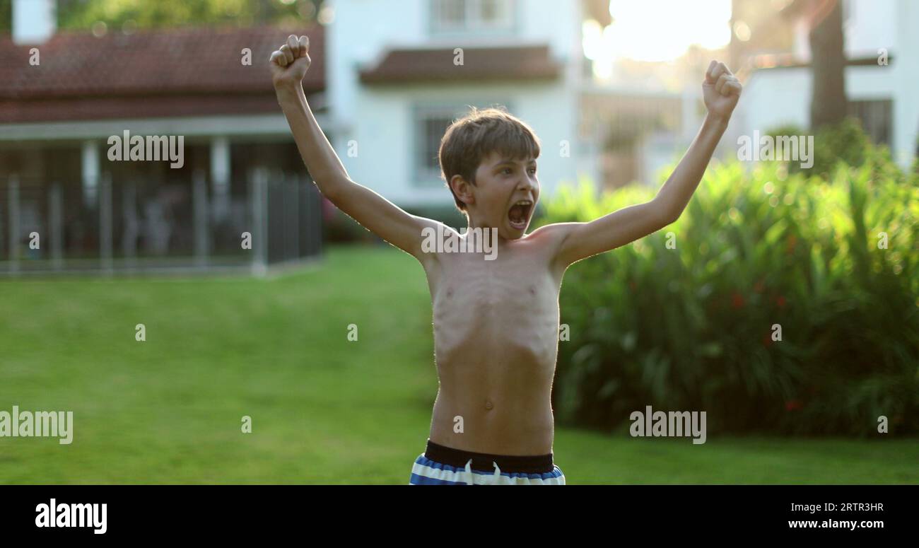 Child raising arms in the air in celebration. Happy victorious young ...