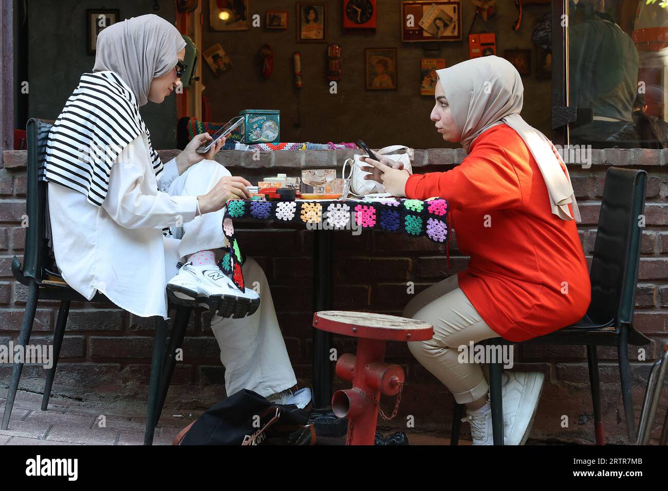 Young muslim women texting on their smartphones at a cafe in the Balat district of Istanbul Stock Photo
