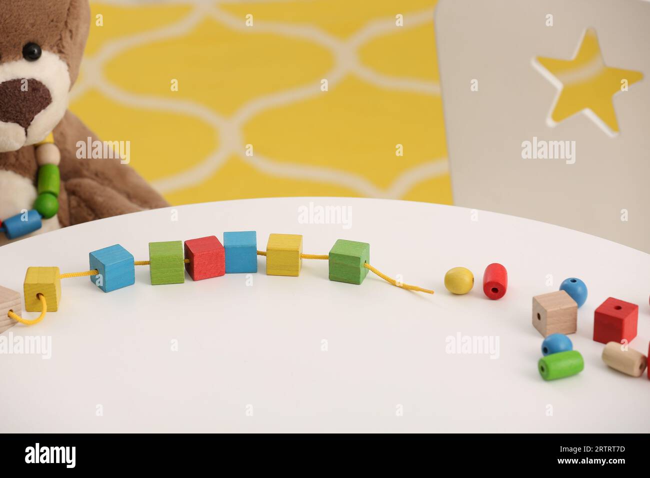 Wooden pieces and string for threading activity on white table. Motor