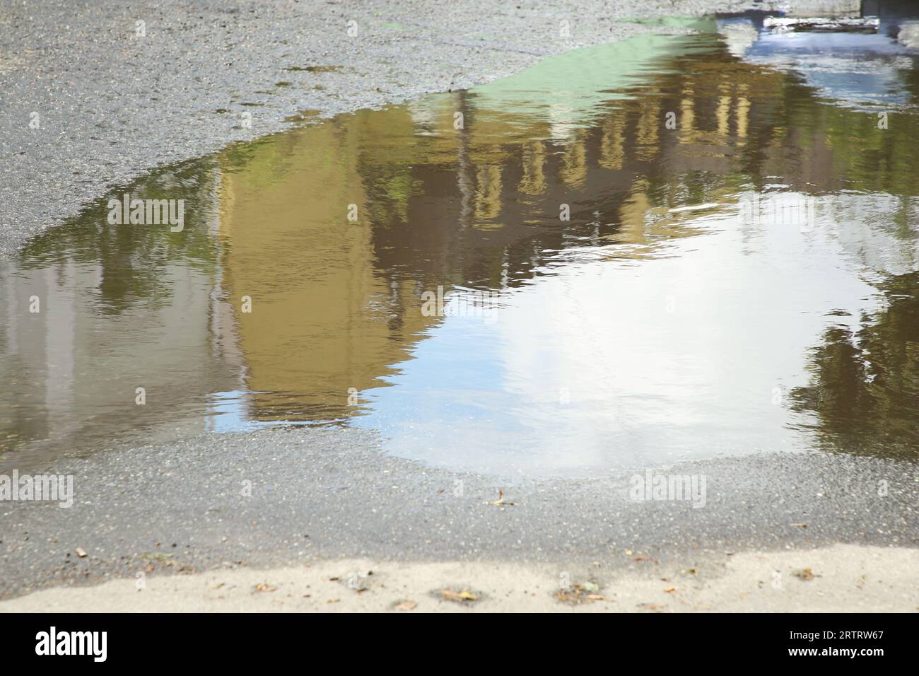 Reflection of buildings in rippled puddle water on asphalt Stock Photo ...