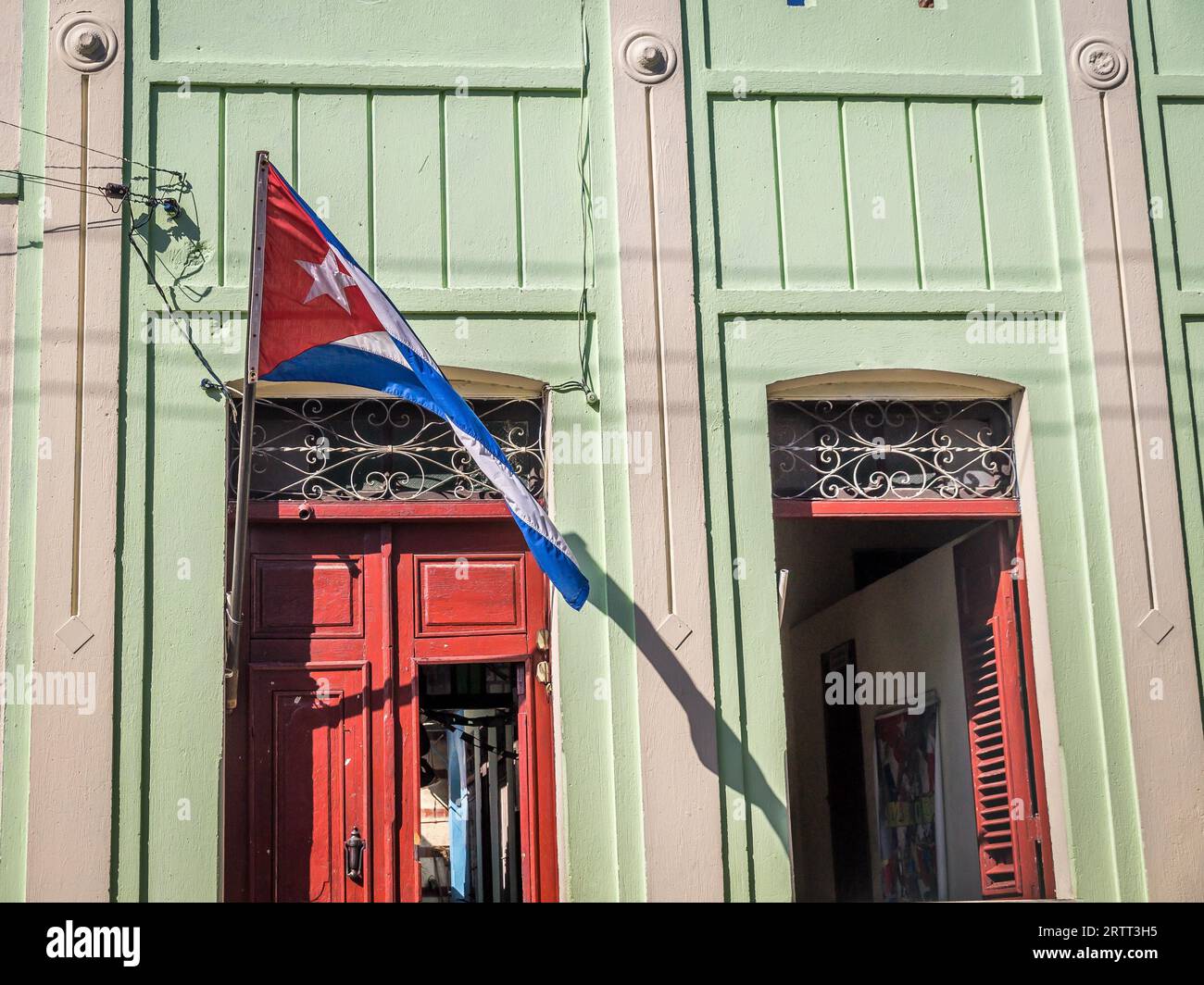 Cuban flag with door and window facade at colonial Cuban house in Santiago de Cuba Stock Photo