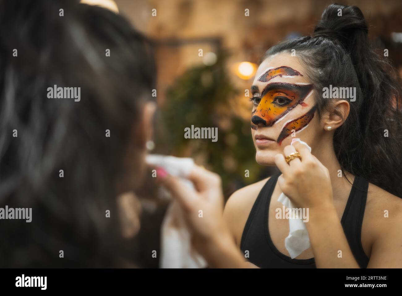 Halloween party hairstyle and makeup preparations, woman with beautiful makeup looking in the mirror Stock Photo