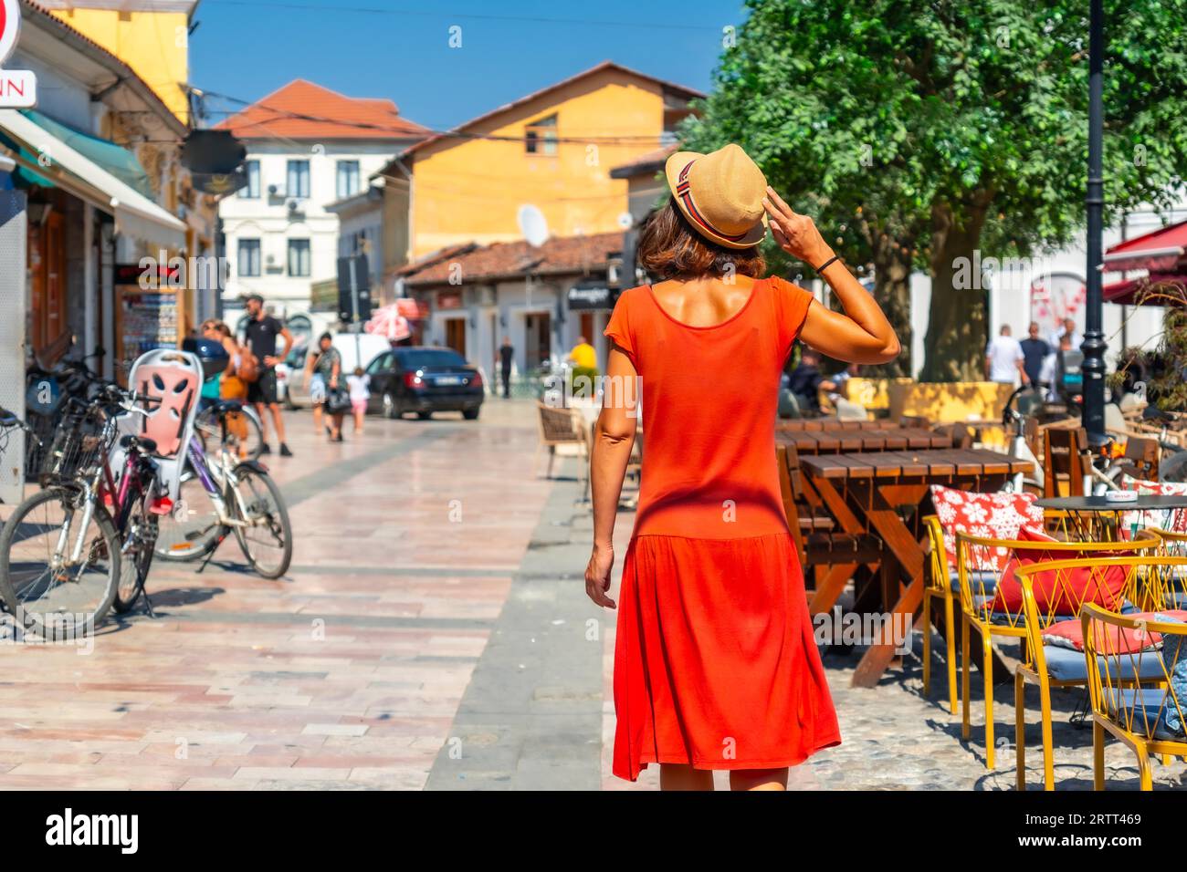 Tourist woman in red dress and hat enjoying vacation walking on the streets of Shkoder city. Albania Stock Photo