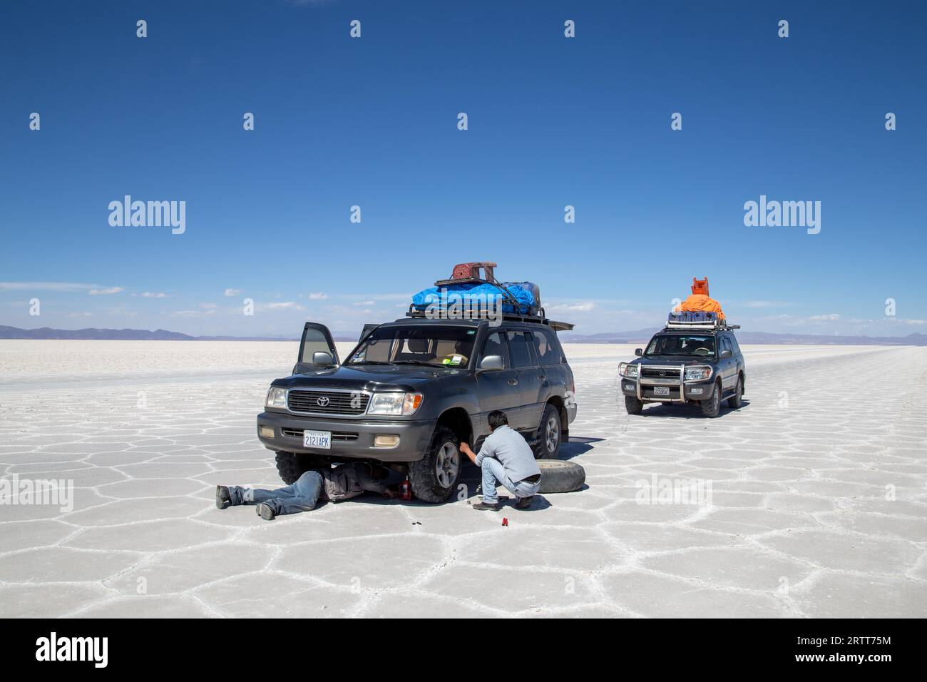 Uyuni, Bolivia, October 31, 2015: Two man changing flat tire of a jeep in the Salar de Uyuni Stock Photo