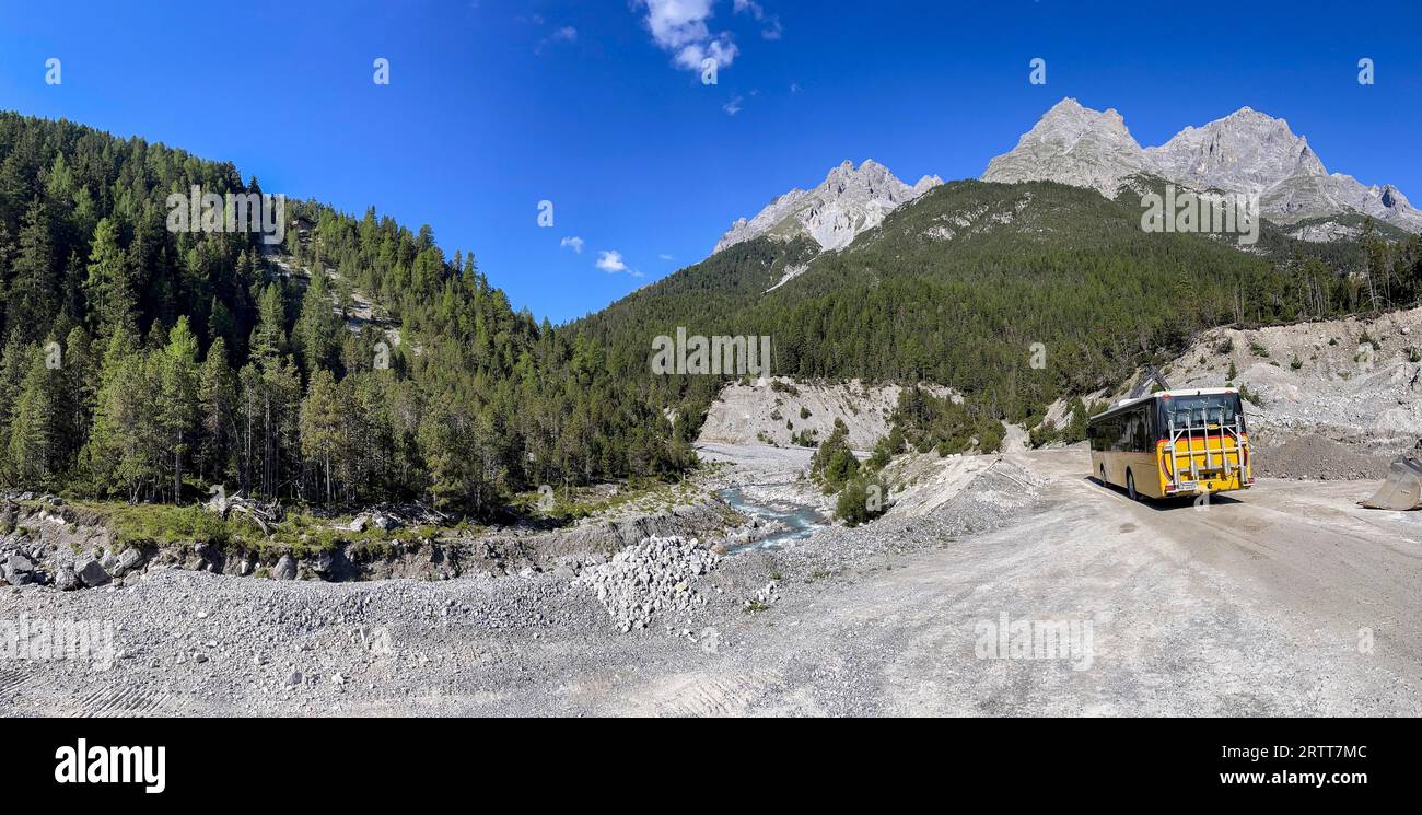 Postbus driving on gravel road in Val S-charl, Engadin, Grisons, Switzerland Stock Photo