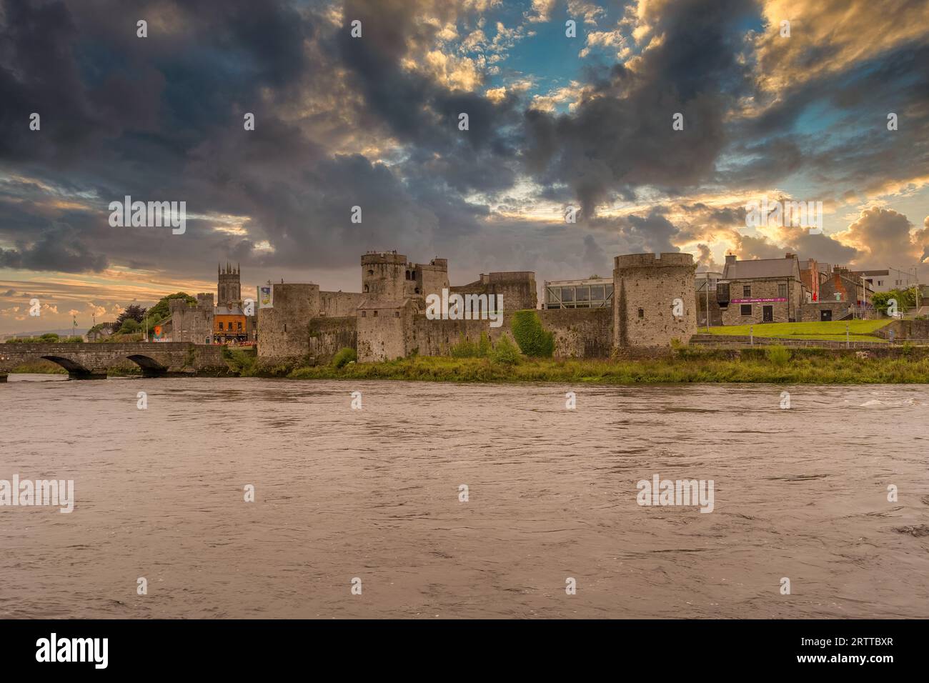 King John castle in Limerick Ireland on the banks of the Shannon river next to the Thomond bridge with dramatic sunset cloudy sky Stock Photo