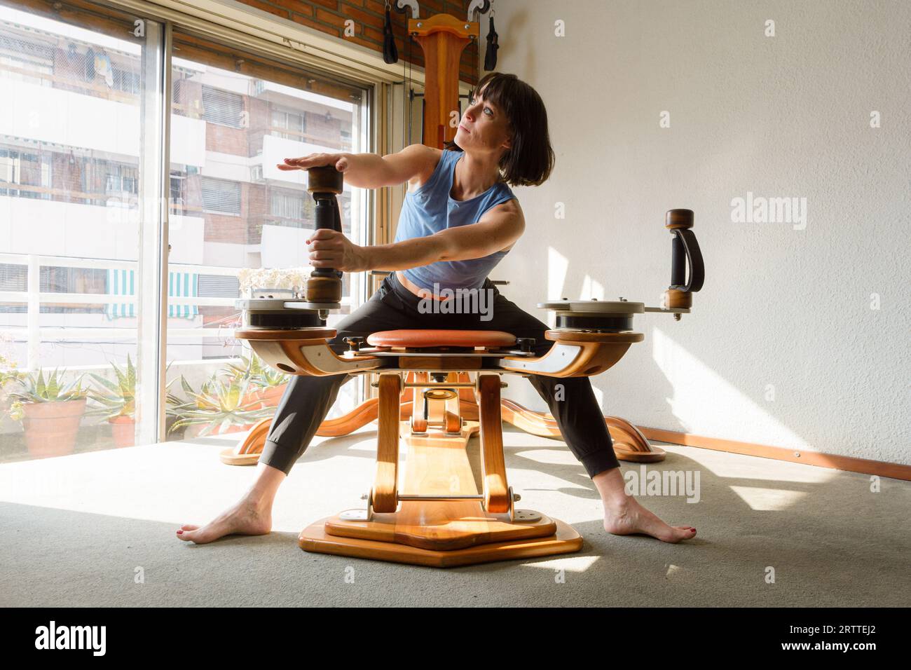 young latin woman in morning at home sitting training and stretching ...