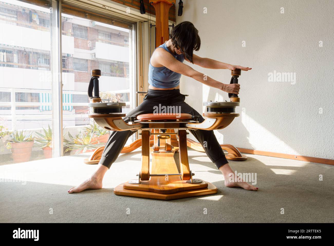 young latin woman in morning at home sitting training and stretching ...