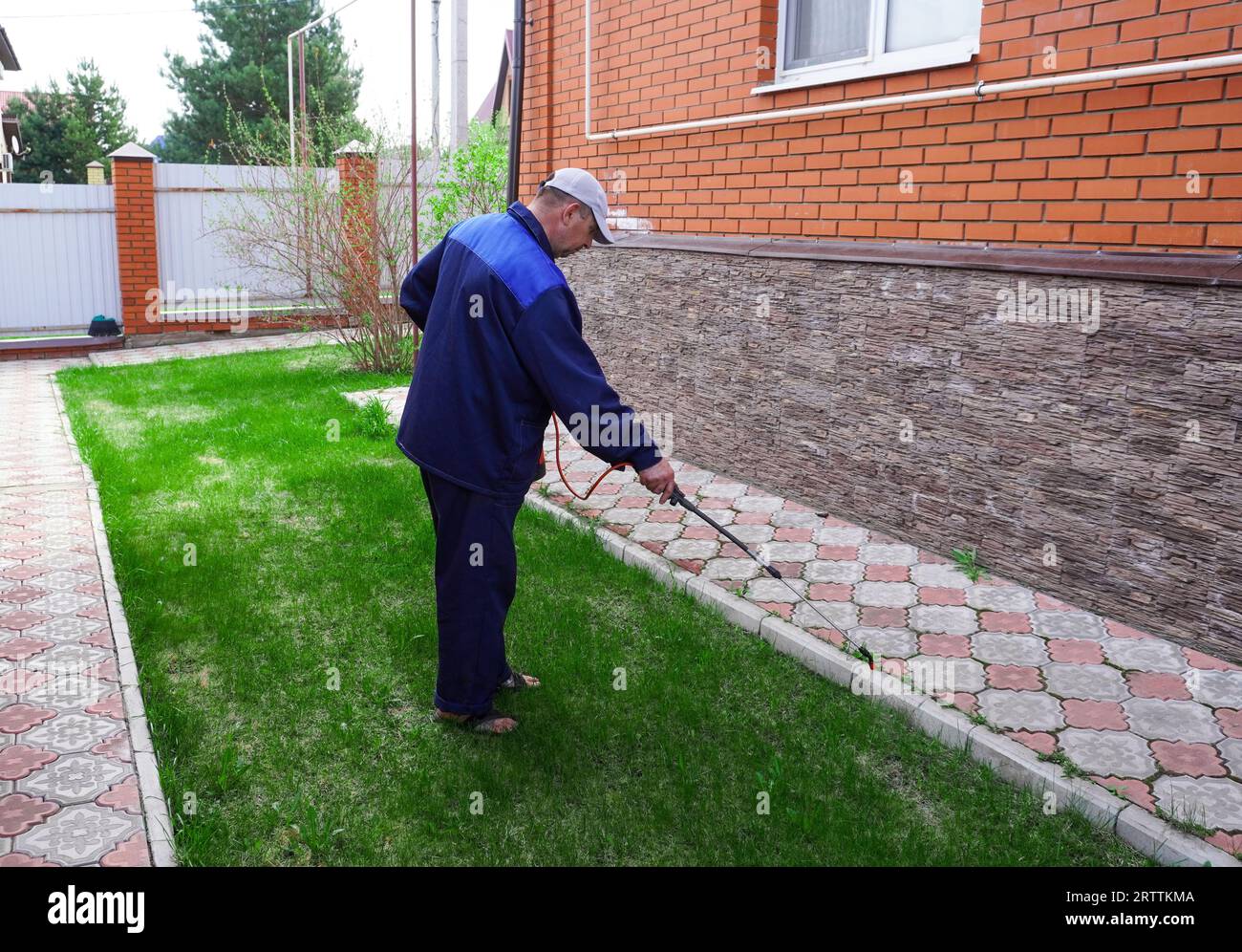 A man works in the garden, spraying weeds from a sprayer Stock Photo ...