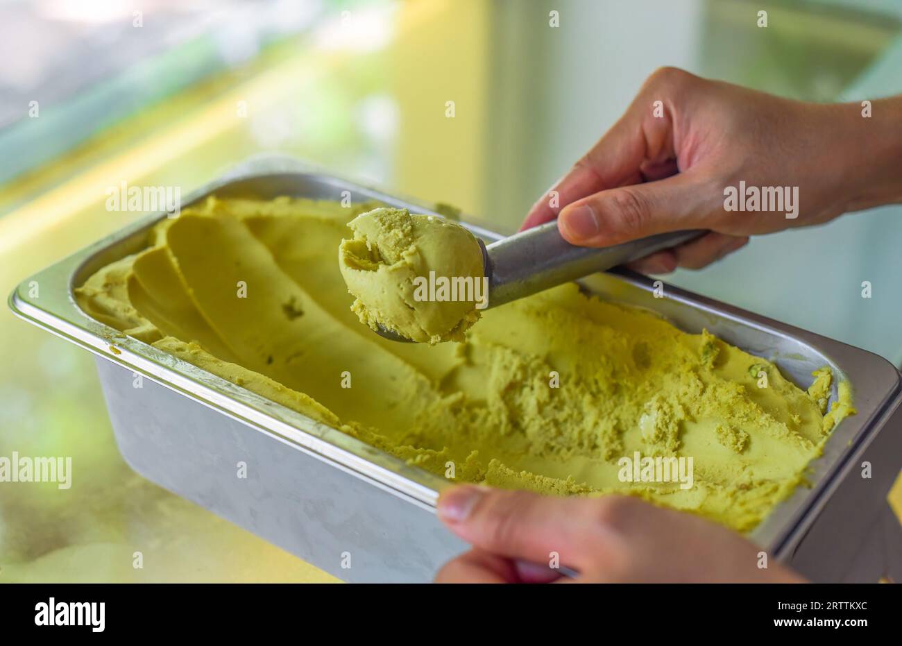 hand scooping a scoop of Avocado ice cream into a spoon in fridge Stock