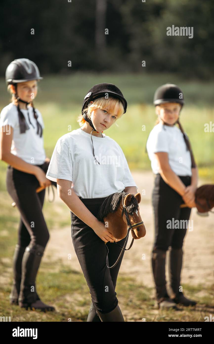 Portrait of a jockey girl who sits on a toy horse. In the background