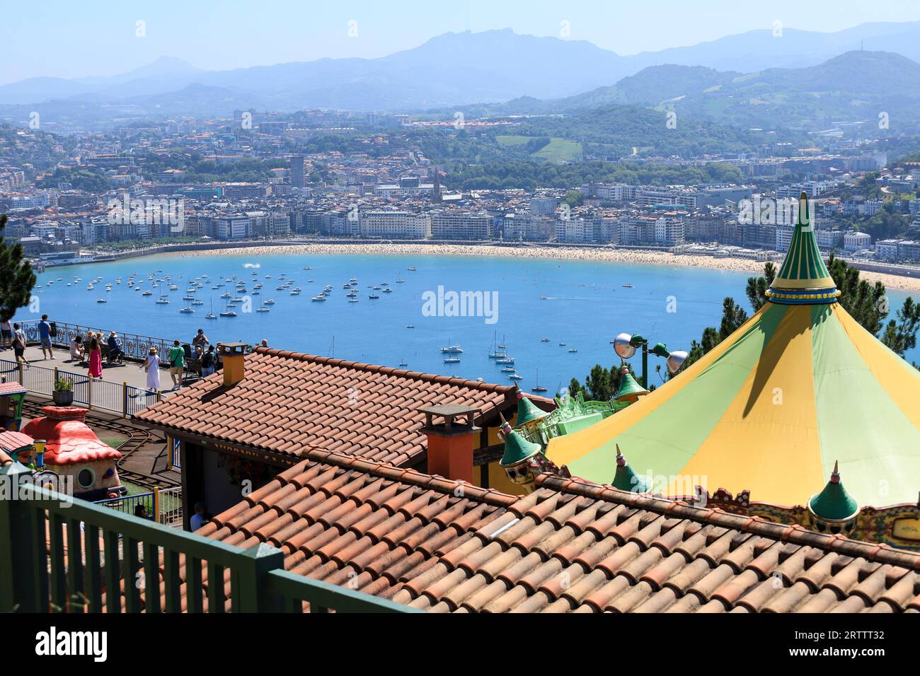 Panoramic view of San Sebastian's La Concha Bay and city skyline seen from Monte Igueldo amusement park, with the historic funicular tracks visible.