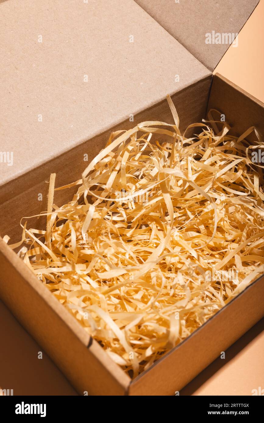 Vertical image of open box with straw lining and copy space over cream ...