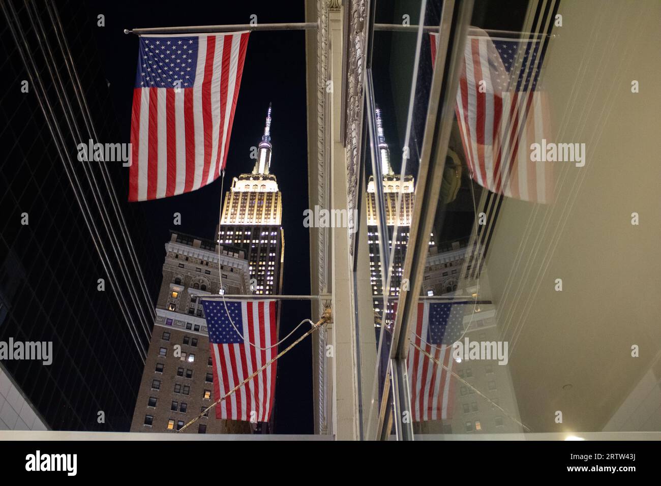 Upward shot of 2 American flags reflecting on mirror, with the empire state building at the top. Manhattan NYC USA Stock Photo